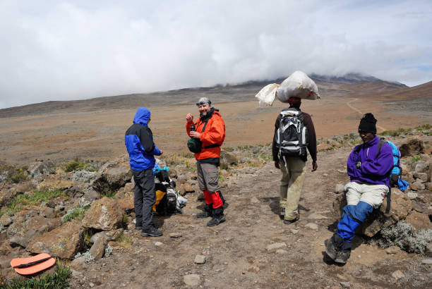 Climbing Mount Kilimanjaro hikers resting during ascent due to altitude sickness challenges on the trail in Tanzania