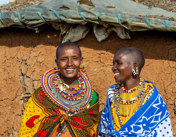 Maasai culture in Tanzania two Maasai women in traditional dress talking outside a traditional house