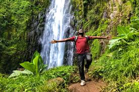Male traveler posing with Materuni Waterfalls in the background, showcasing Materuni Waterfalls highlights in Tanzania