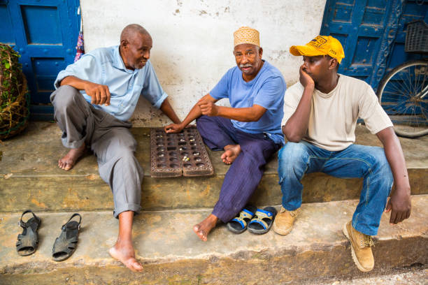 Swahili Culture Traditions in Zanzibar showing African, Arabian, and Indian men playing traditional Mancala board game in Stone Town Tanzania