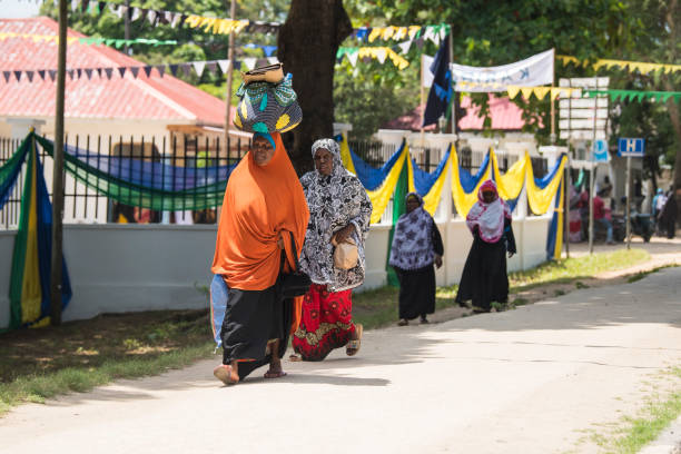 Swahili Culture Traditions in Zanzibar showing daily street life with locals wearing traditional dress along the road in Stone Town Tanzania