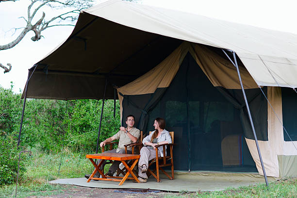 Tanzania safari cost tips – young couple in safari clothes relaxing outside a mid-range tented camp